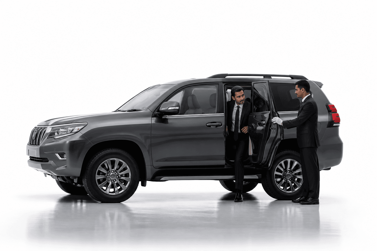 Chauffeur welcoming a passenger beside a graphite Toyota Land Cruiser Prado